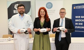 Drei Personen halten VR-Brillen in der Hand und blicken in die Kamera