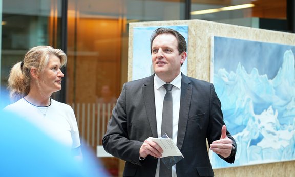 Limnologin Birgit Sattler und Klimalandesrat René Zumtobel bei der Eröffnung der Ausstellung. Im Hintergrund die Fotografien des Gletschereises.