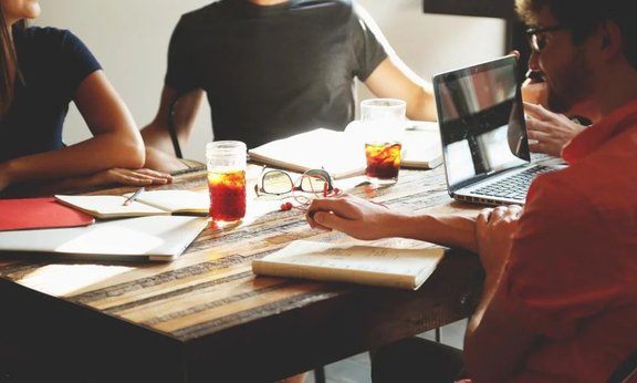 Drei Teammitglieder an einem Tisch mit Arbeitsunterlagen