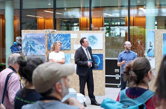 Birgit Sattler und Landesrat René Zumtobel bei der Eröffnung der Ausstellung. Im Hintergrund die Fotografien des blauen Gletschereises.