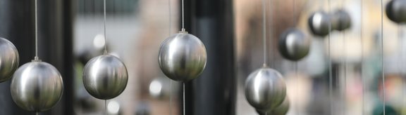 Sechs Menschen stehen im Kreis und legen die Hände aufeinander für Teamwork